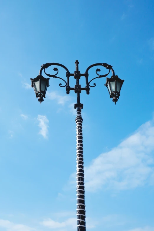 an ornate street lamp on a pole against a blue sky