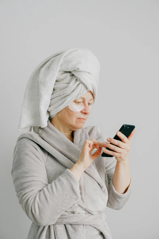 a woman in a white towel holding a cellphone