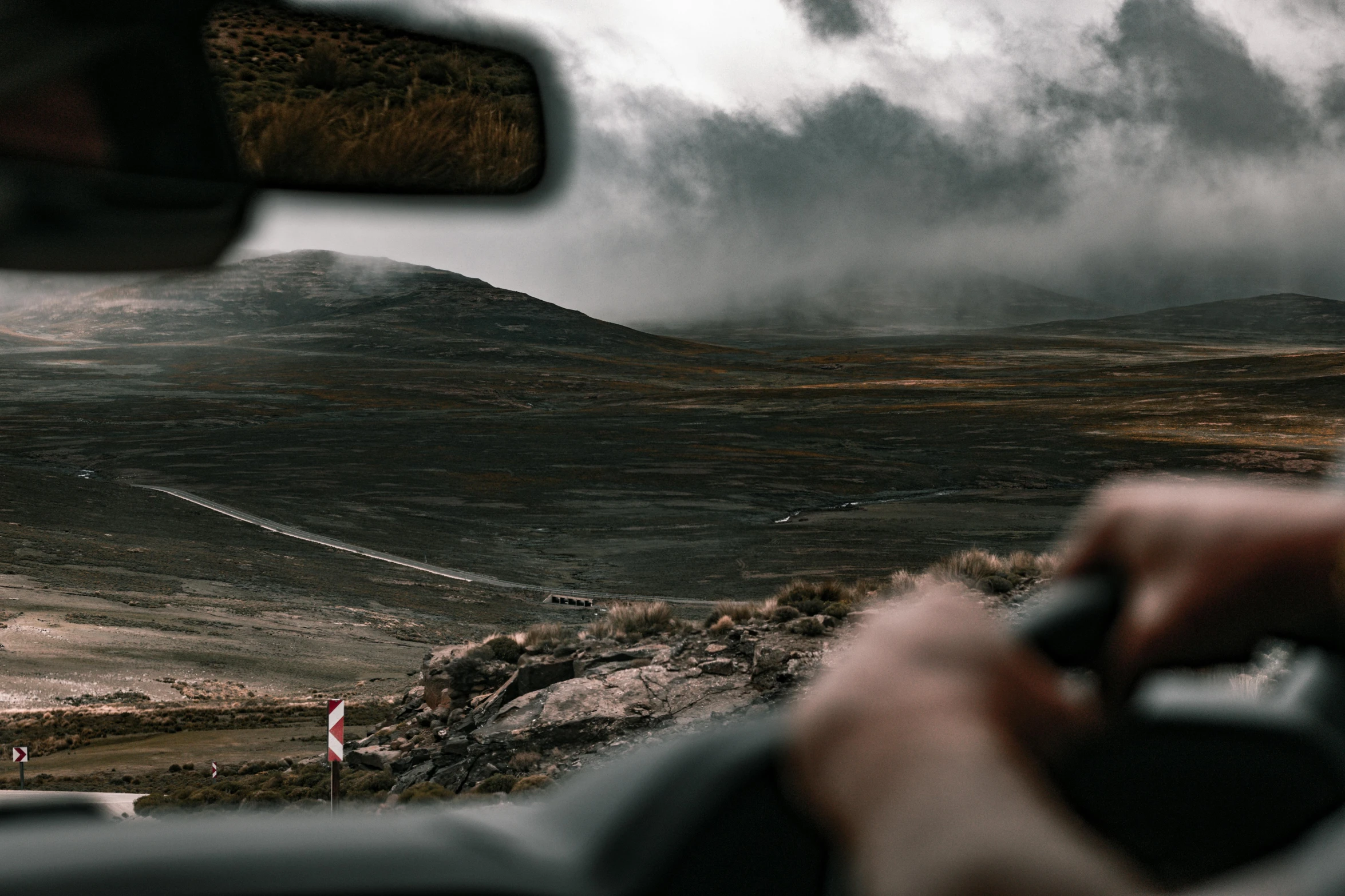 a person driving down a road near some hills