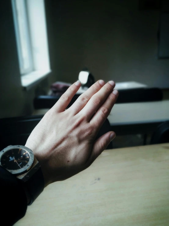 an hand is outstretched towards the light from a window