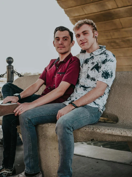 two men sitting on a cement bench