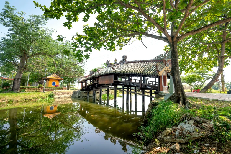 a wooden bridge over a lake near trees and buildings