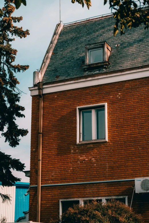 the roof on this brick building has windows that look out into a city