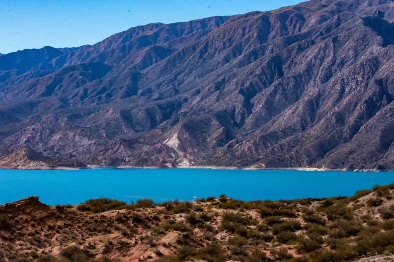 a blue lake near some mountains, with no one around it