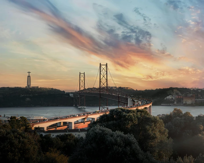 a train going over a bridge that is lit up at dusk