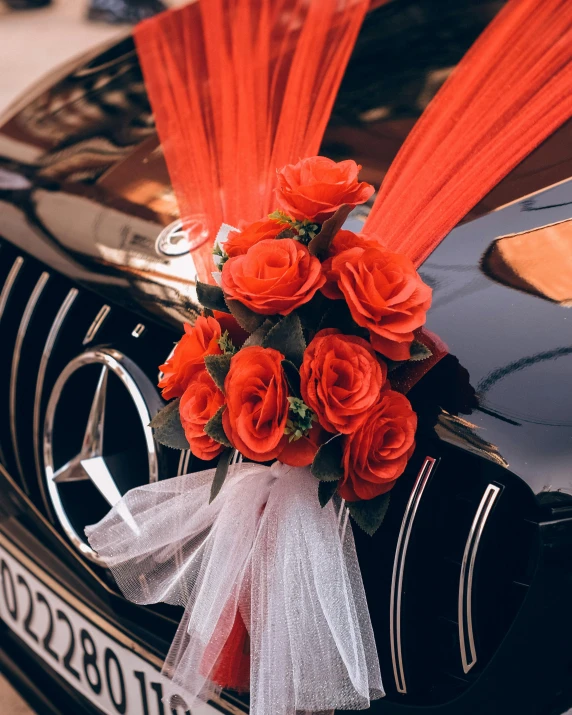 a bouquet of orange roses on top of the hood of a car