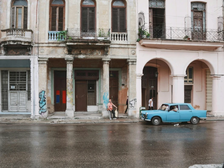 a blue car parked on the street in front of a row of old buildings