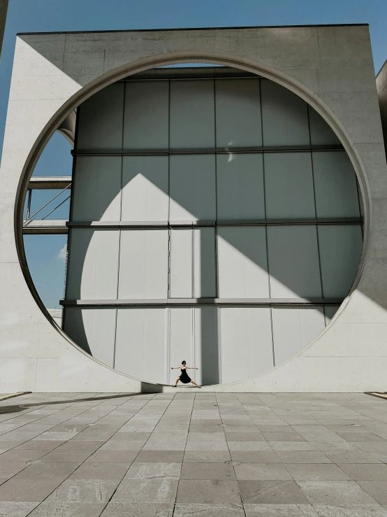 a stone building with a circular window and a concrete walkway next to it