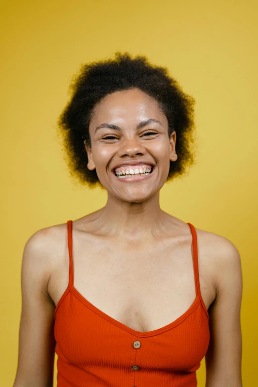 a woman with short hair and an orange shirt smiles at the camera