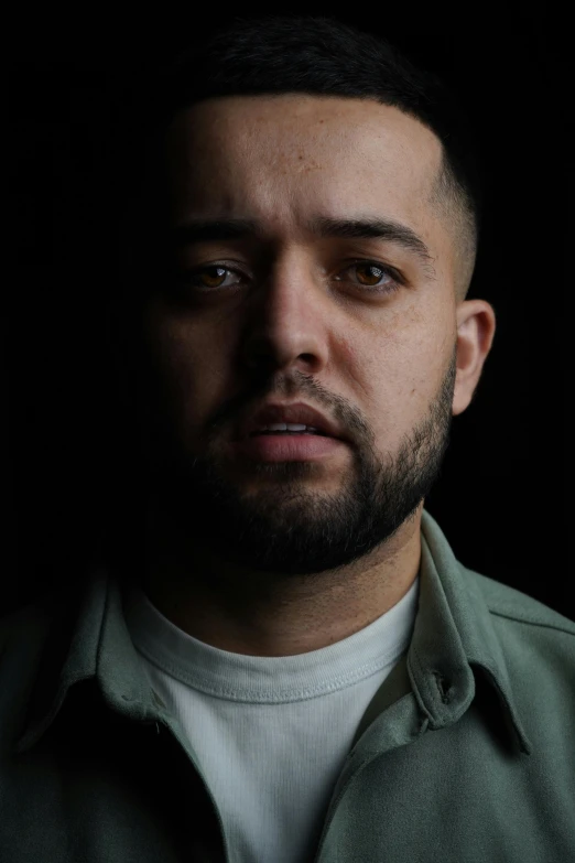 a man with a beard standing in front of a dark background