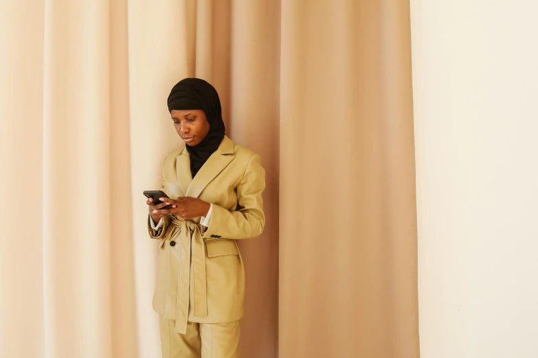 a black woman in a suit is standing with a cellphone