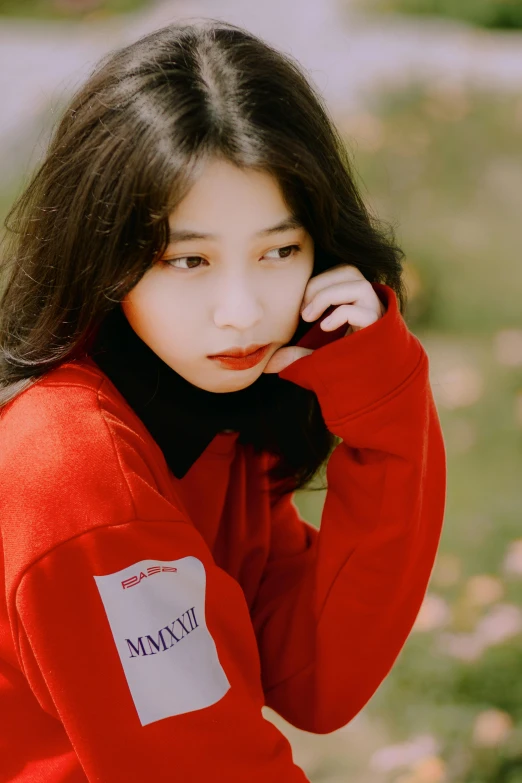 young woman with red sweatshirt leaning on arm