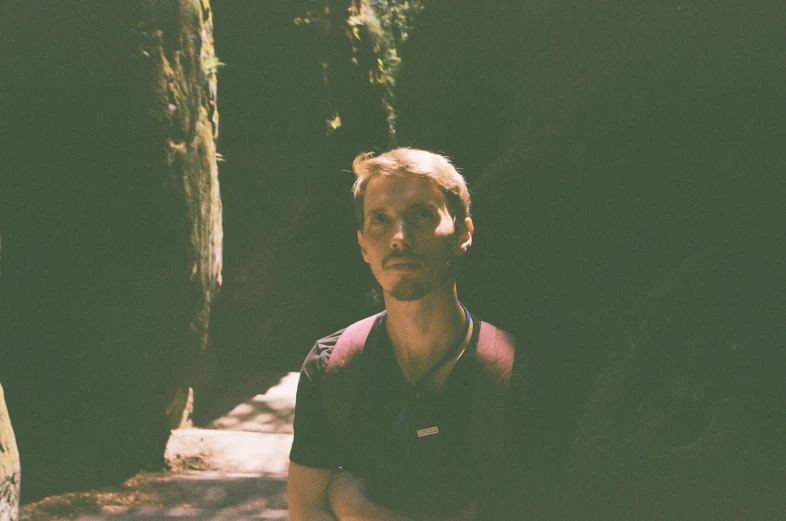 a man sitting down next to a tree in the woods