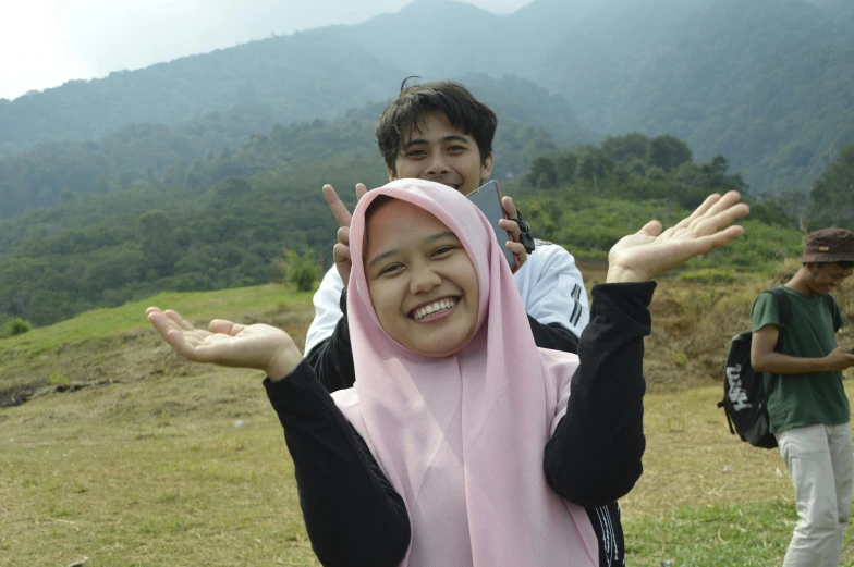 two people posing for a picture while one of them is wearing a pink headscarf