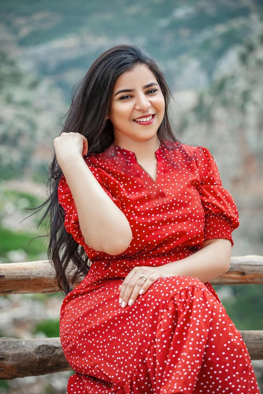 a young woman with a smile on her face and dress sitting outside