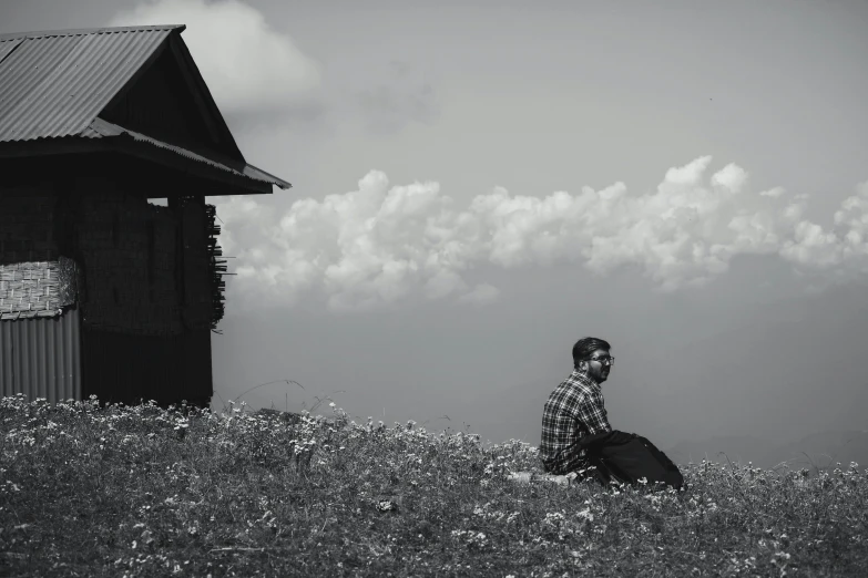 a man sitting in the grass by a building