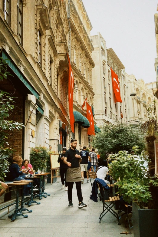 several people are sitting and walking through an outdoor cafe