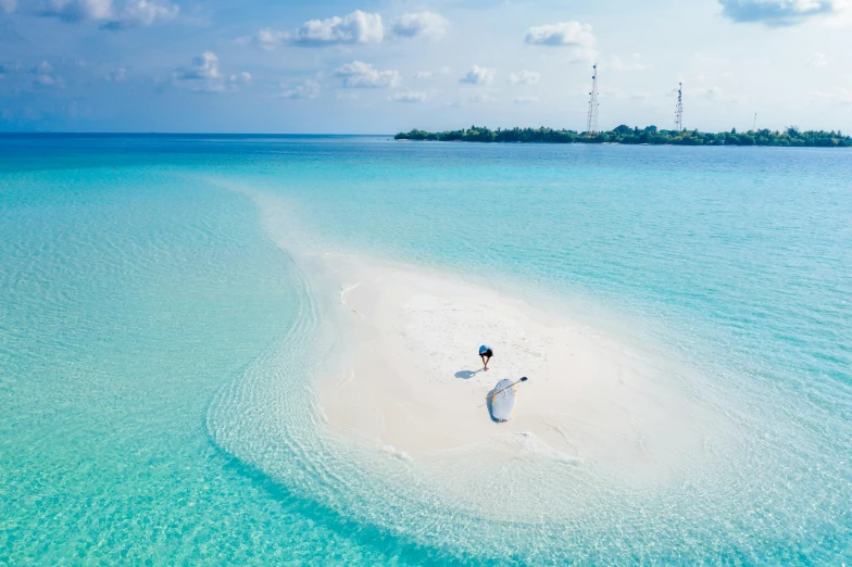 an airplane flying over a white sandy island