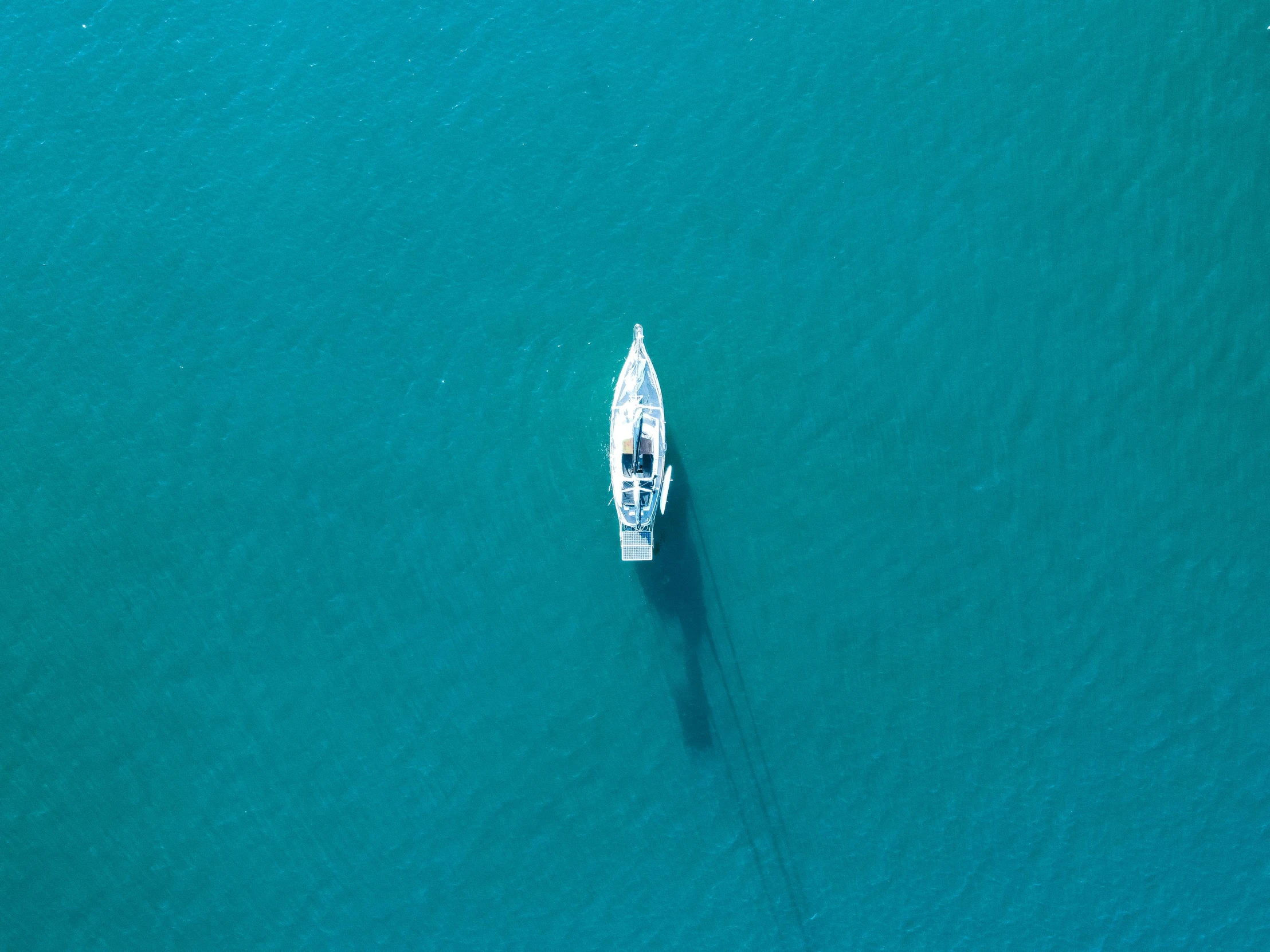 a small boat floating in the ocean on top of blue water