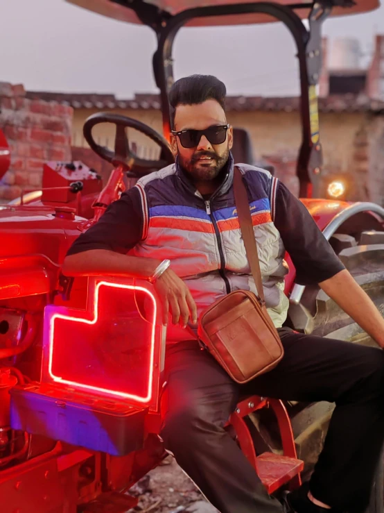 a man sitting on top of a red tractor with his bag in hand