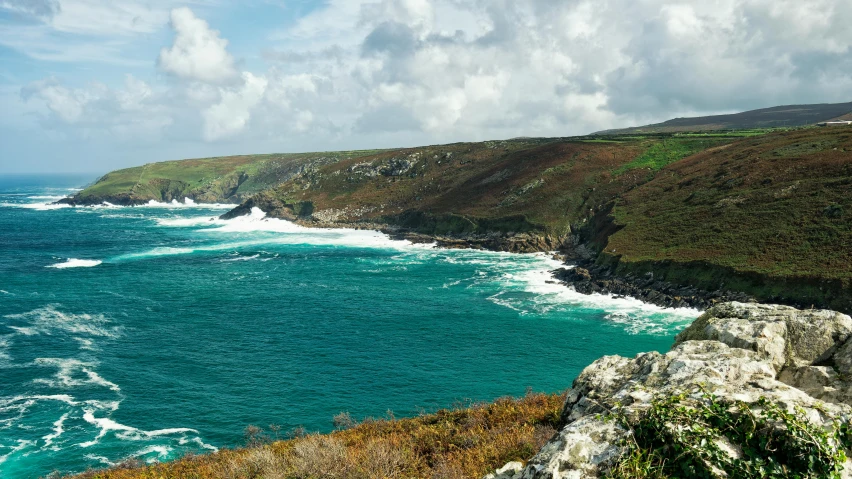 ocean with green rocky coastline and water with white foamy waves