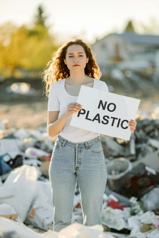 a woman standing on the street holding a no plastic sign