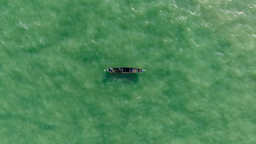 a lone boat floating on the water in clear green waters