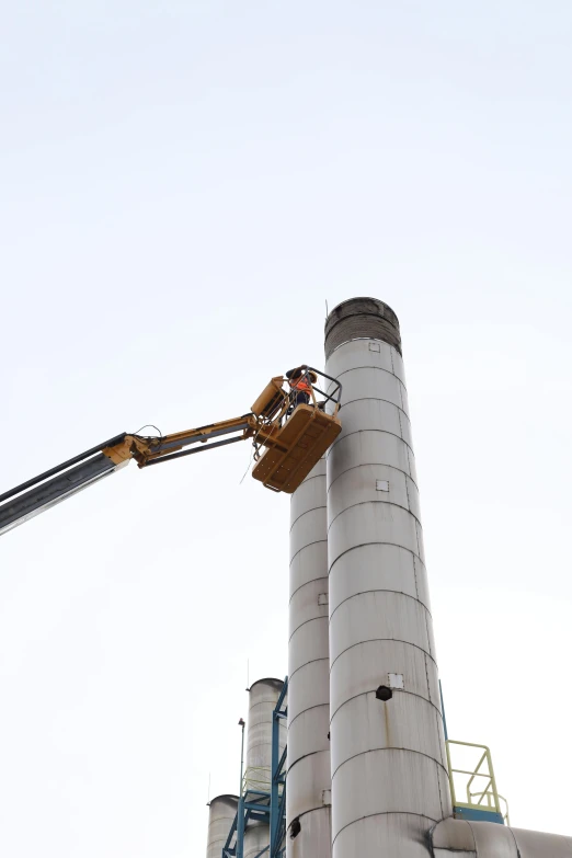 a big crane is operating on a cement tower