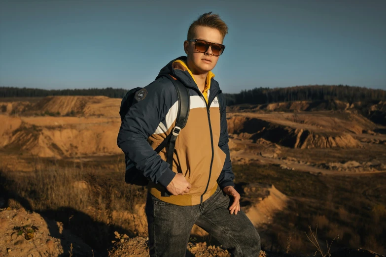 a young man is standing on top of the mountain