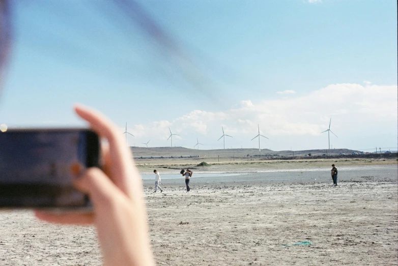 some people are walking on the beach while someone takes a picture