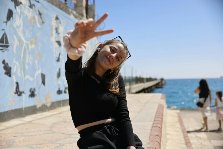 girl standing on the sidewalk waving for the camera