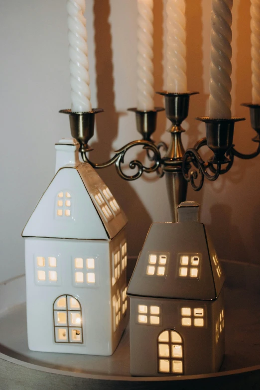 two candles sit next to each other near a model house