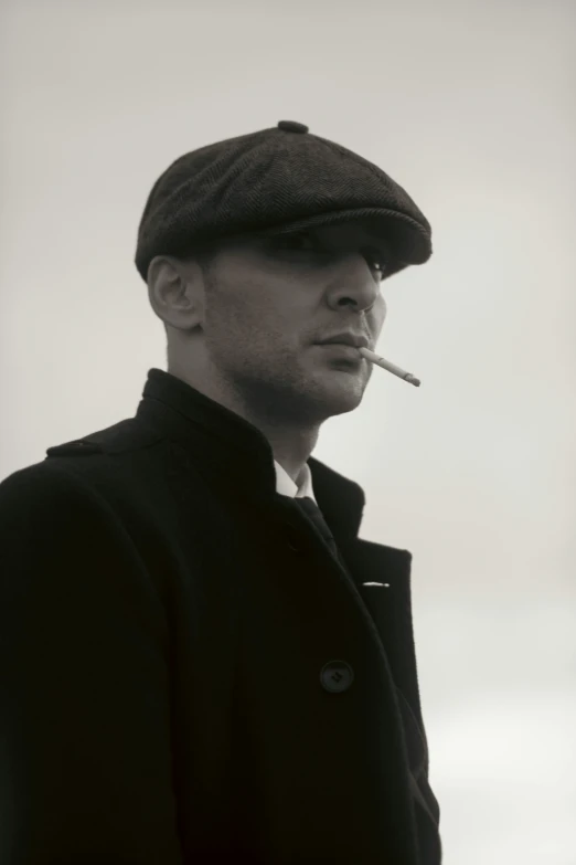 a man in black jacket and hat smoking a cigarette