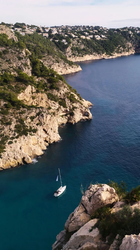 a boat floating on the water near a rocky shoreline