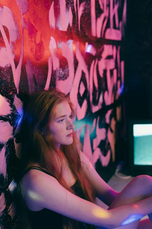a girl sitting in front of some graffiti