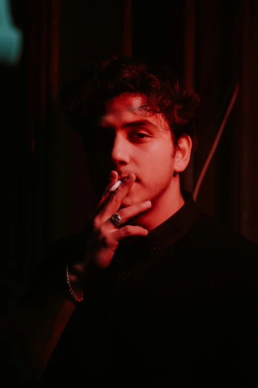 man in dark posing with cigarette and ring