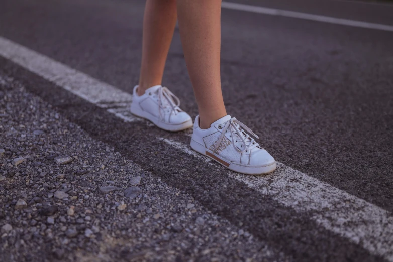 two people in white sneakers are crossing a street