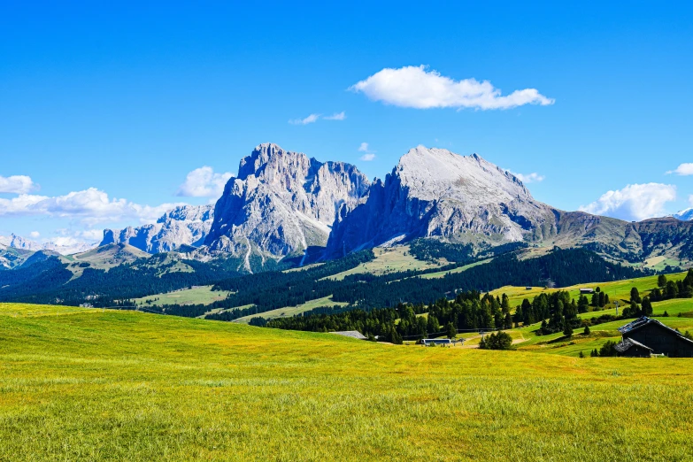 the mountains look down upon a valley and a barn in front of it