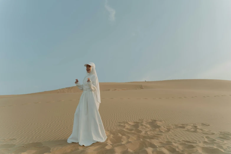 a woman wearing a veil and white dress in the desert