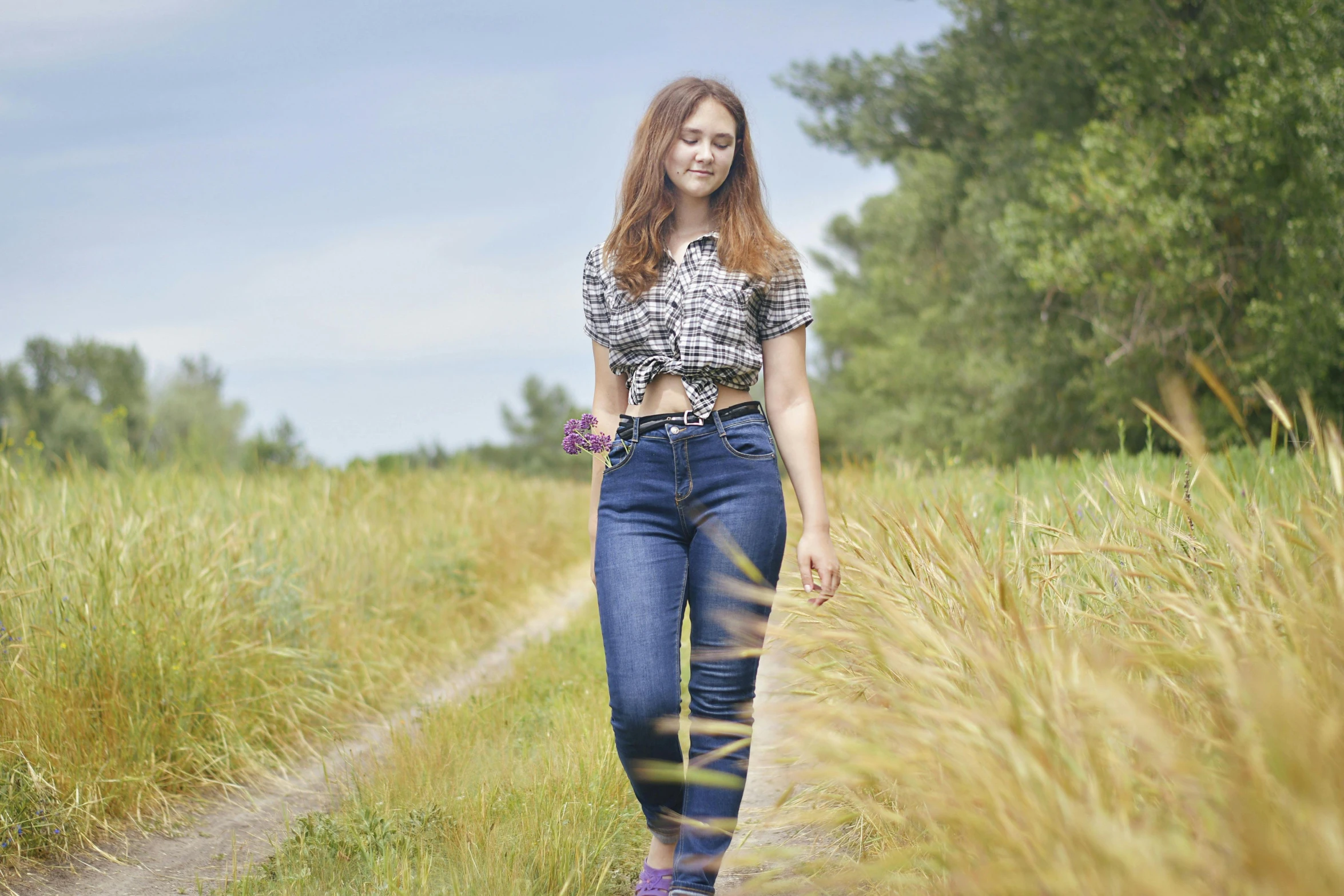 young female walking down the side walk in tall grass