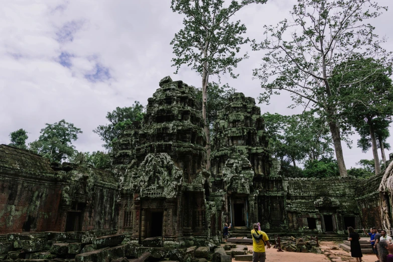 a couple of people standing in front of trees near a stone building