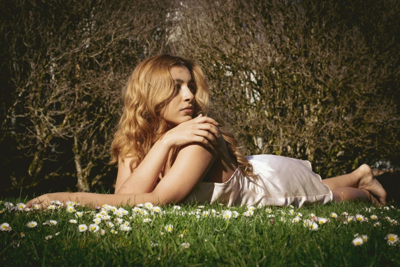 a pretty girl laying in the grass with her arms around herself