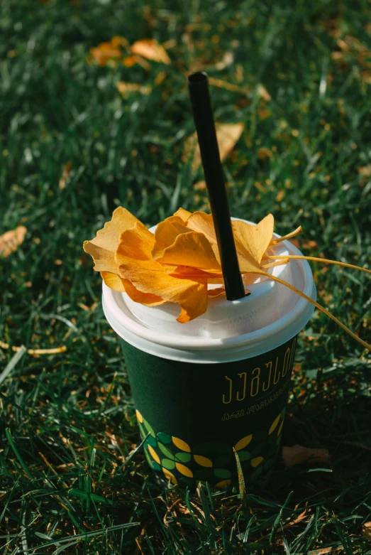 a cup with yellow flowers sitting in a field