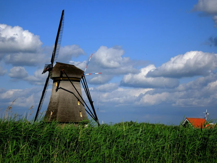 an old mill sitting next to a house in a field