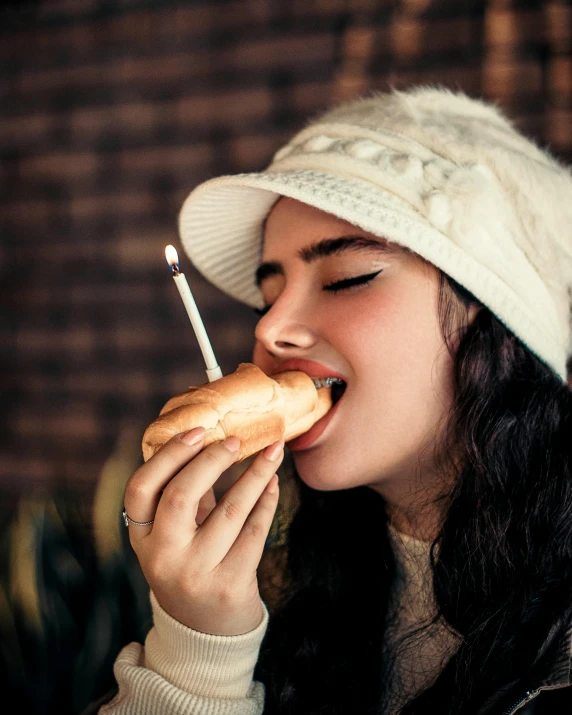 a woman wearing a hat biting on a  dog