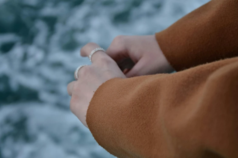 a hand holding onto an object in front of a body of water