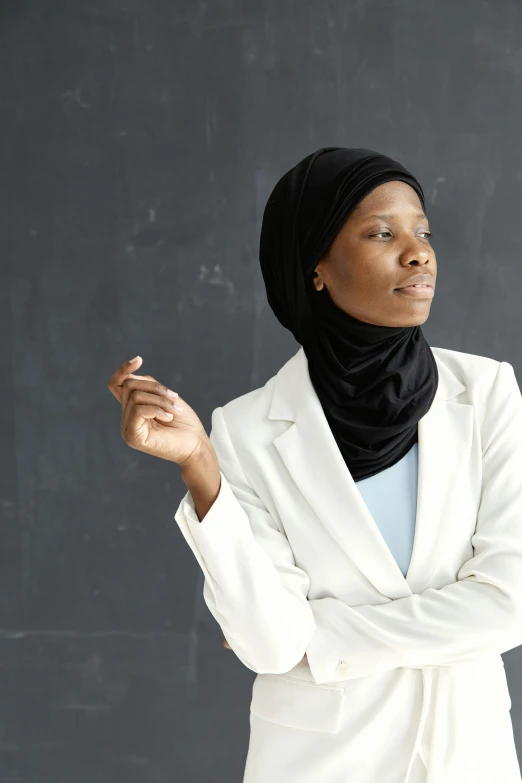 a woman in a white suit holding her hands on a blackboard