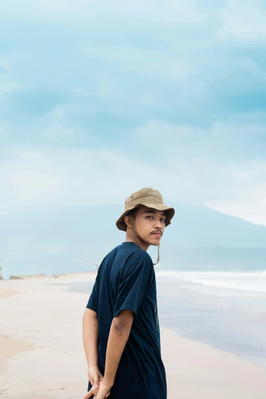 a man in a hat walking along the beach