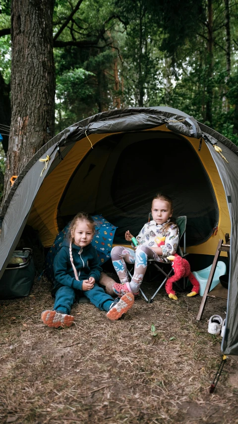 two children are sitting in a tent on the ground