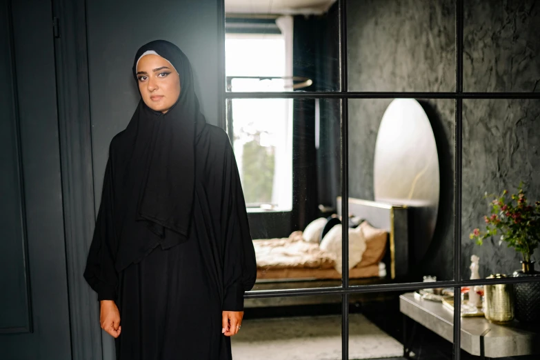 woman in black outfit standing beside window with furniture